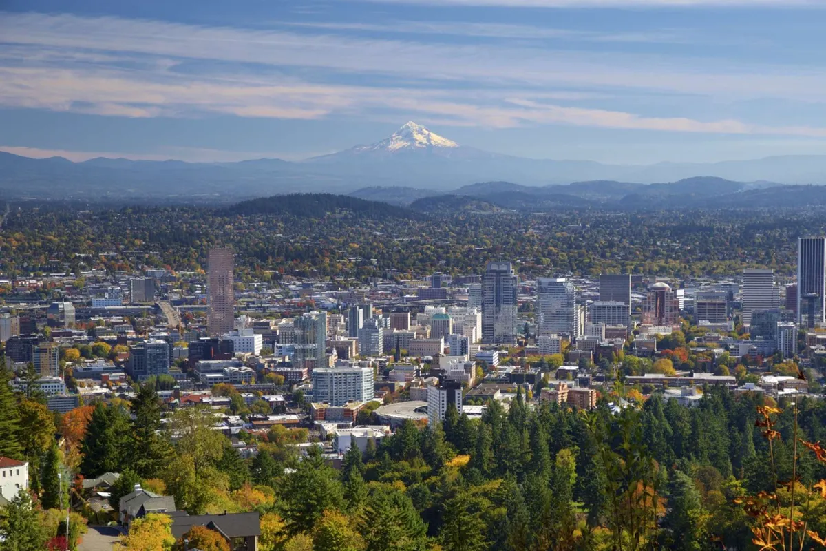A panoramic view featuring Mount Hood rising above the downtown Portland skyline, surrounded by lush greenery. The vibrant scene captures the area’s natural beauty and the variety of recreational activities available in the region.