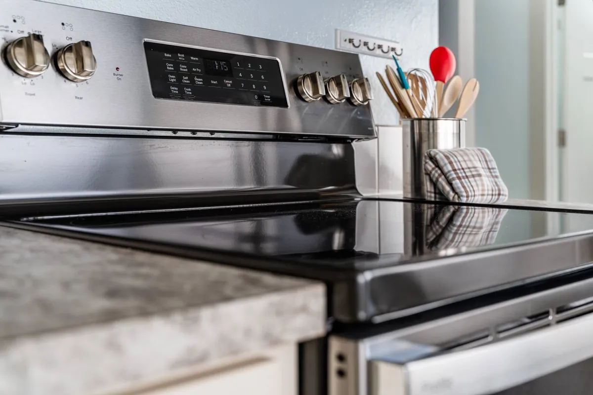 A bright, modern kitchen featuring a stylish stove, utensil holder, and ample counter space, evoking a sense of warmth and home-like comfort. The scene suggests opportunities for couples to share meals or prepare dinner together after a day out.
