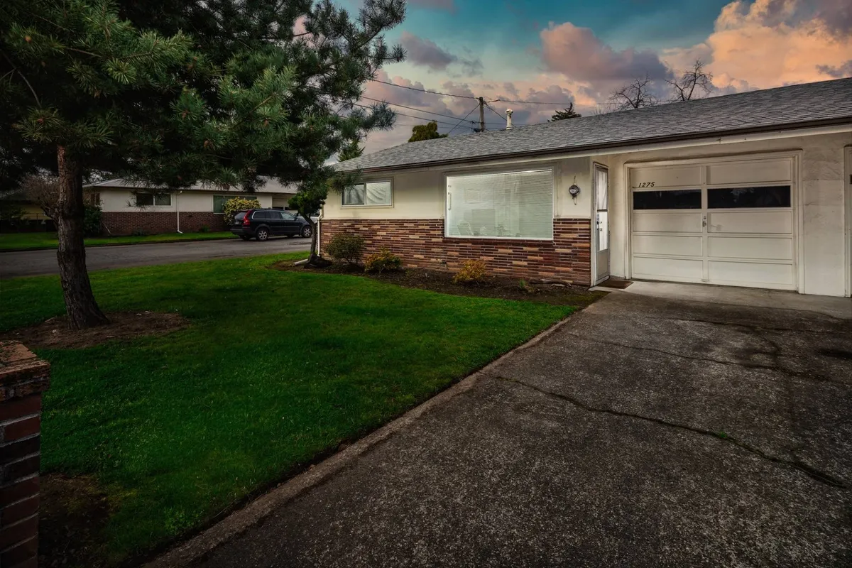 The exterior view of a brick home with a large window, front yard, and driveway, exuding a welcoming and tranquil mood. While focused primarily on the front, it hints at the overall private and homey atmosphere of the property, suggesting a peaceful retreat just steps from city life.