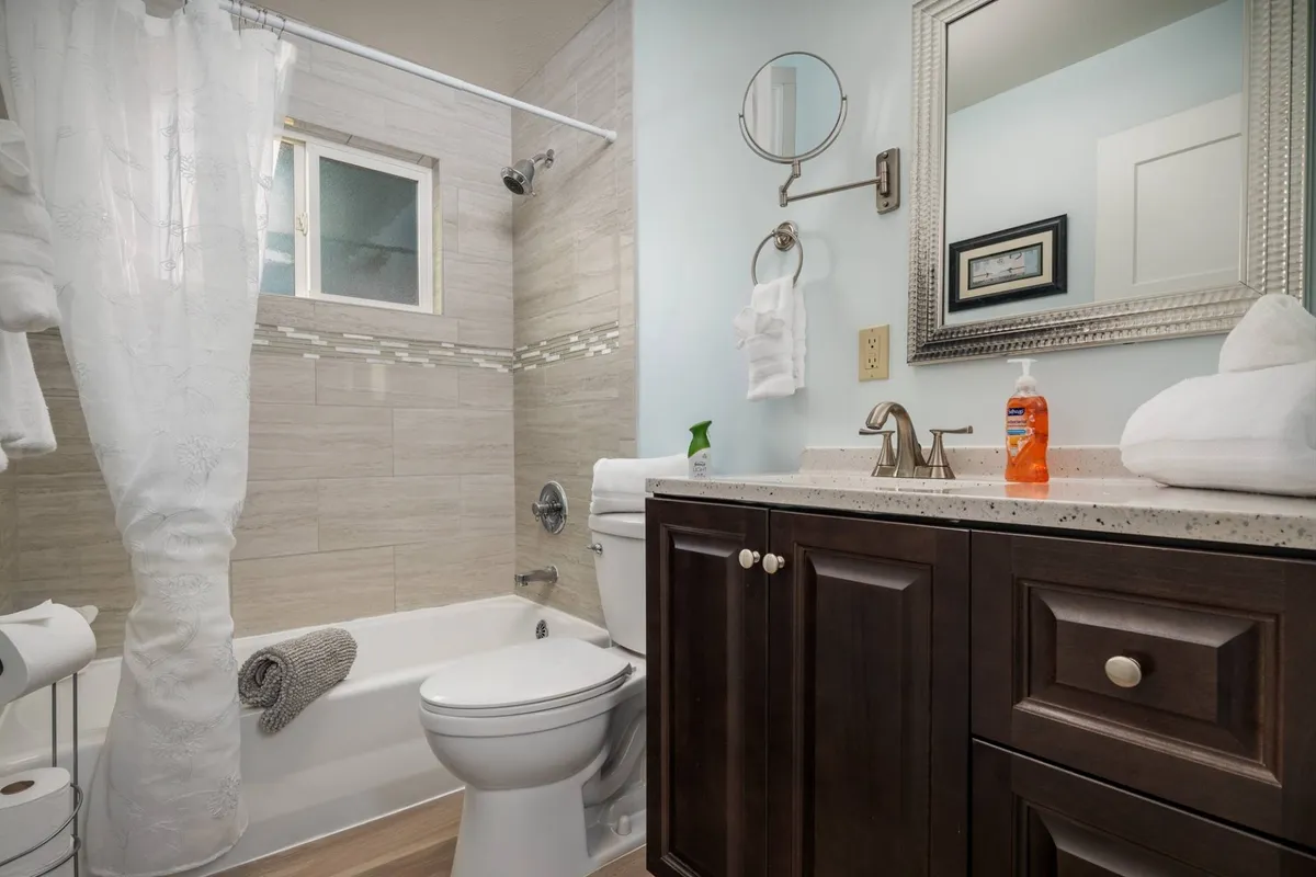 A recently remodeled bathroom featuring a modern vanity with mirror, bathtub, towel rack, and a shower curtain. The clean lines and abundance of light give the space a fresh, rejuvenating feel.